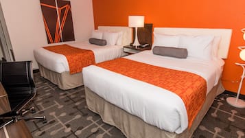 Habitación de hotel con dos camas, un escritorio y una silla.