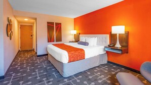 Una habitación de hotel con cama, dos lámparas de noche, una mesita de noche y una silla.