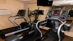 Un gimnasio con cintas de correr, elípticas y una pantalla de televisión.