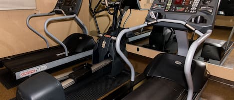 Un gimnasio con cintas de correr, elípticas y una pantalla de televisión.