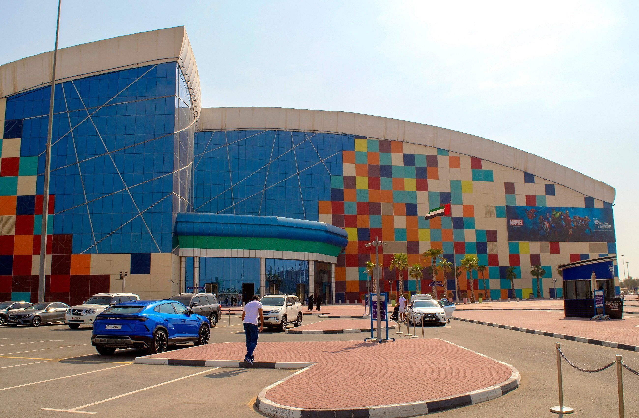 A large, curved building with a colorful facade and a parking lot in front.