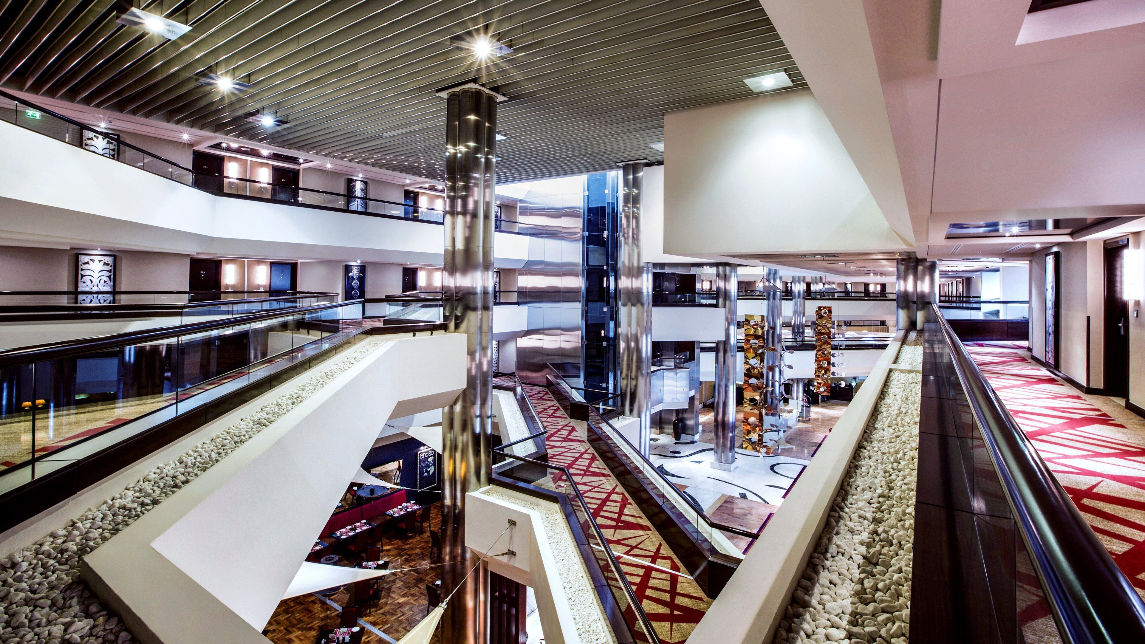 A multi-level atrium with glass railings, a central column, and a patterned carpet.