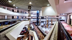 Ein mehrgeschossiges Atrium mit Glasgeländern, einer zentralen Säule und einem gemusterten Teppich.