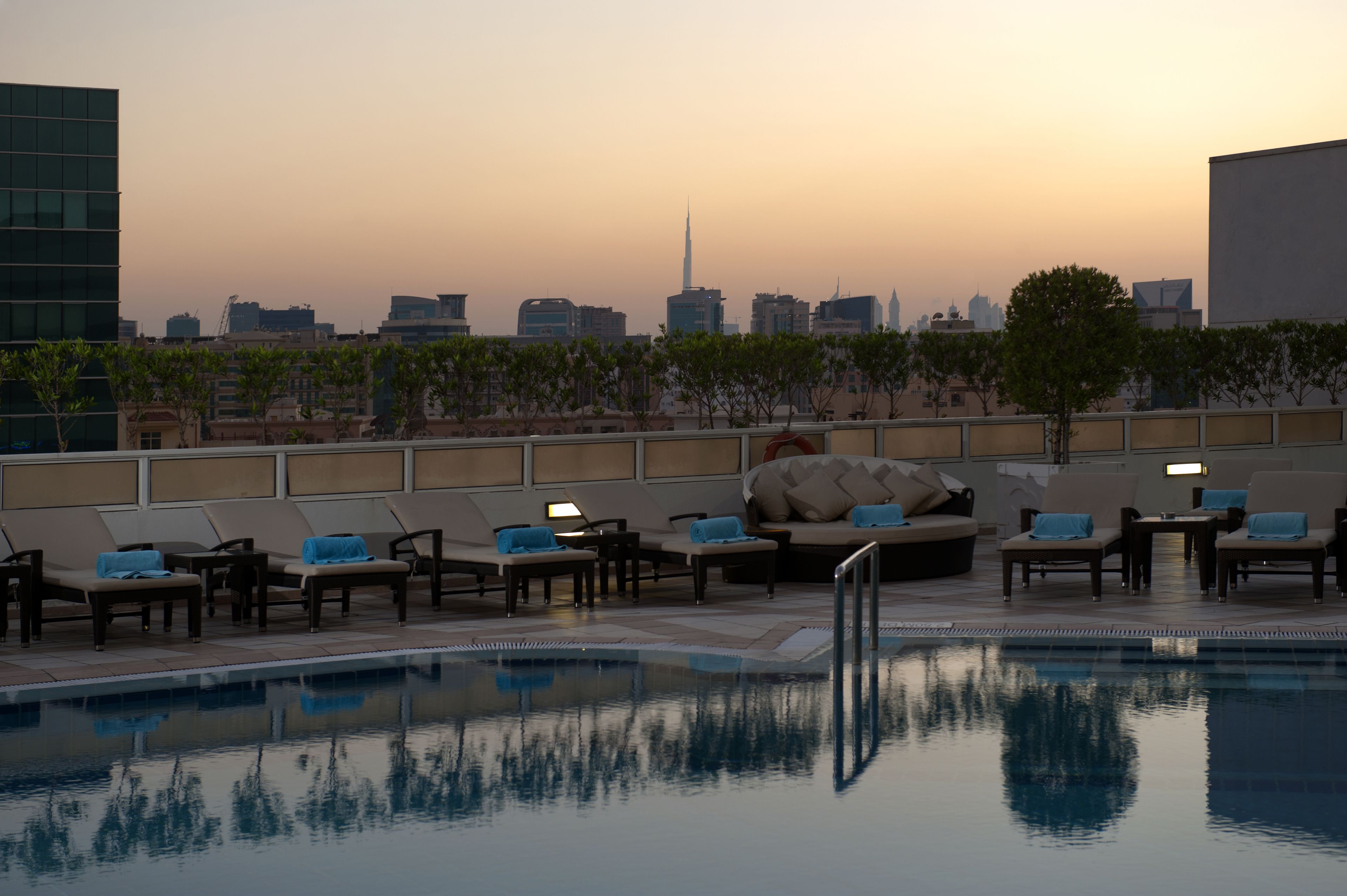 Un espace piscine aménagé sur le toit, avec des chaises longues et une vue sur le panorama urbain.
