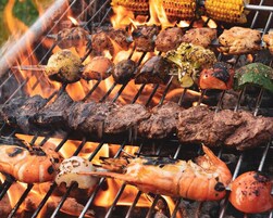 Ein Grill mit verschiedenen Fleisch- und Gemüsesorten, die über offenem Feuer zubereitet werden.