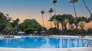A swimming pool surrounded by palm trees and a gazebo.