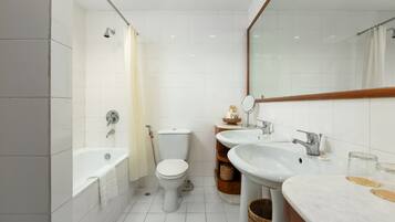 Un baño moderno con bañera, inodoro y dos lavamanos.