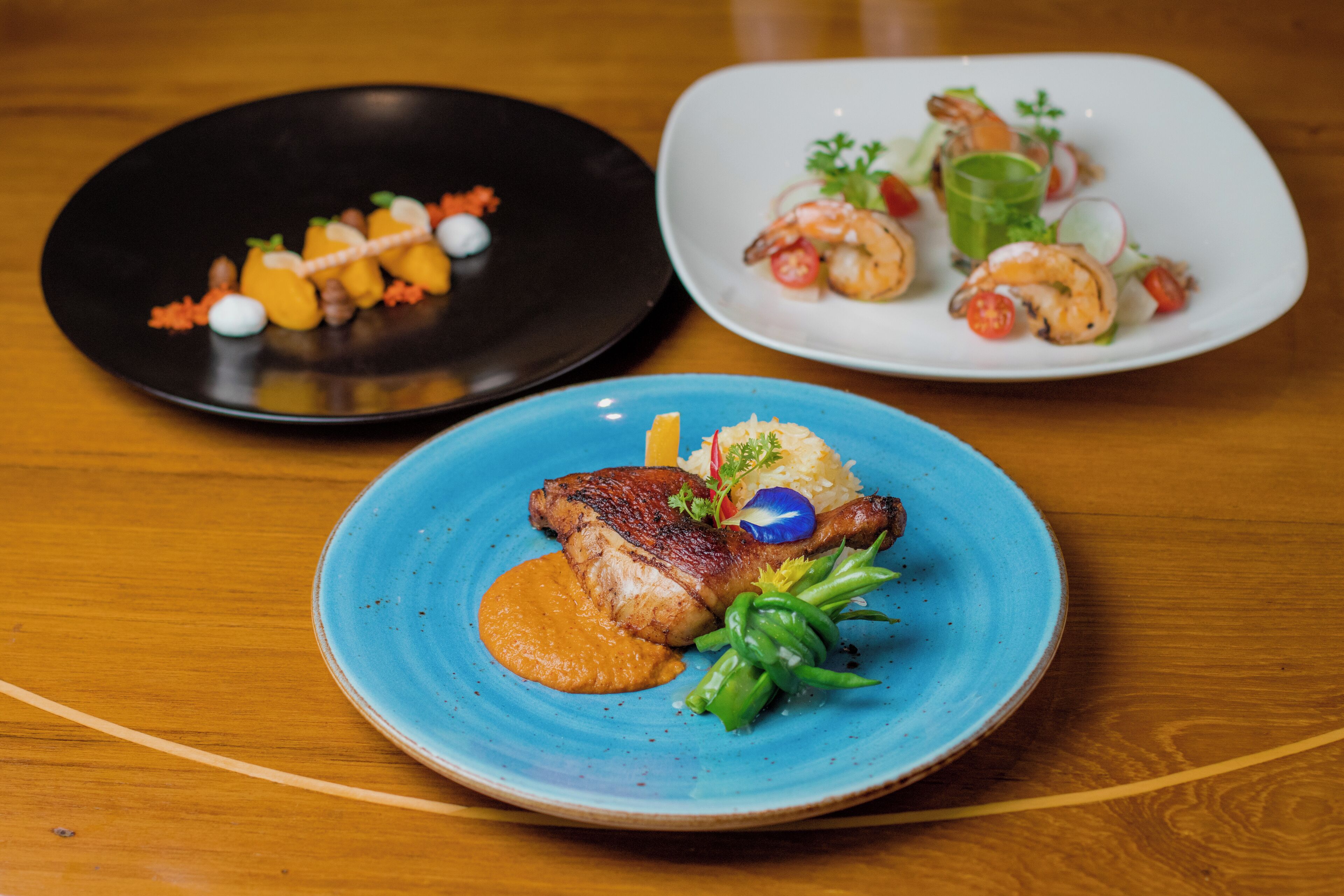 Three plates of food on a wooden table.