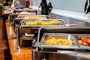 A buffet with various food items, including fruits and vegetables, arranged in metal containers.
