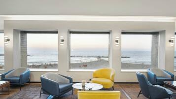 A modern lounge with large windows offering a view of the beach and ocean.
