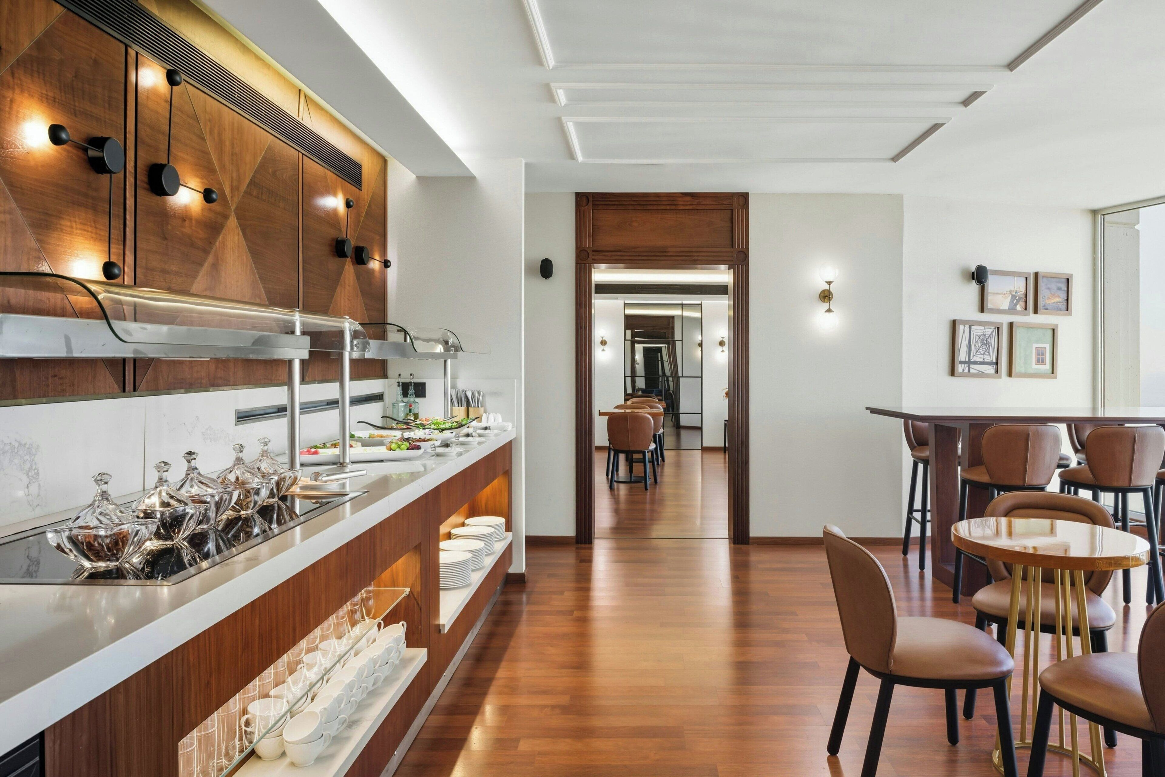 Una cucina moderna con mobili in legno, un'isola in acciaio inossidabile e un'area pranzo con sedie marroni e un tavolo rotondo.