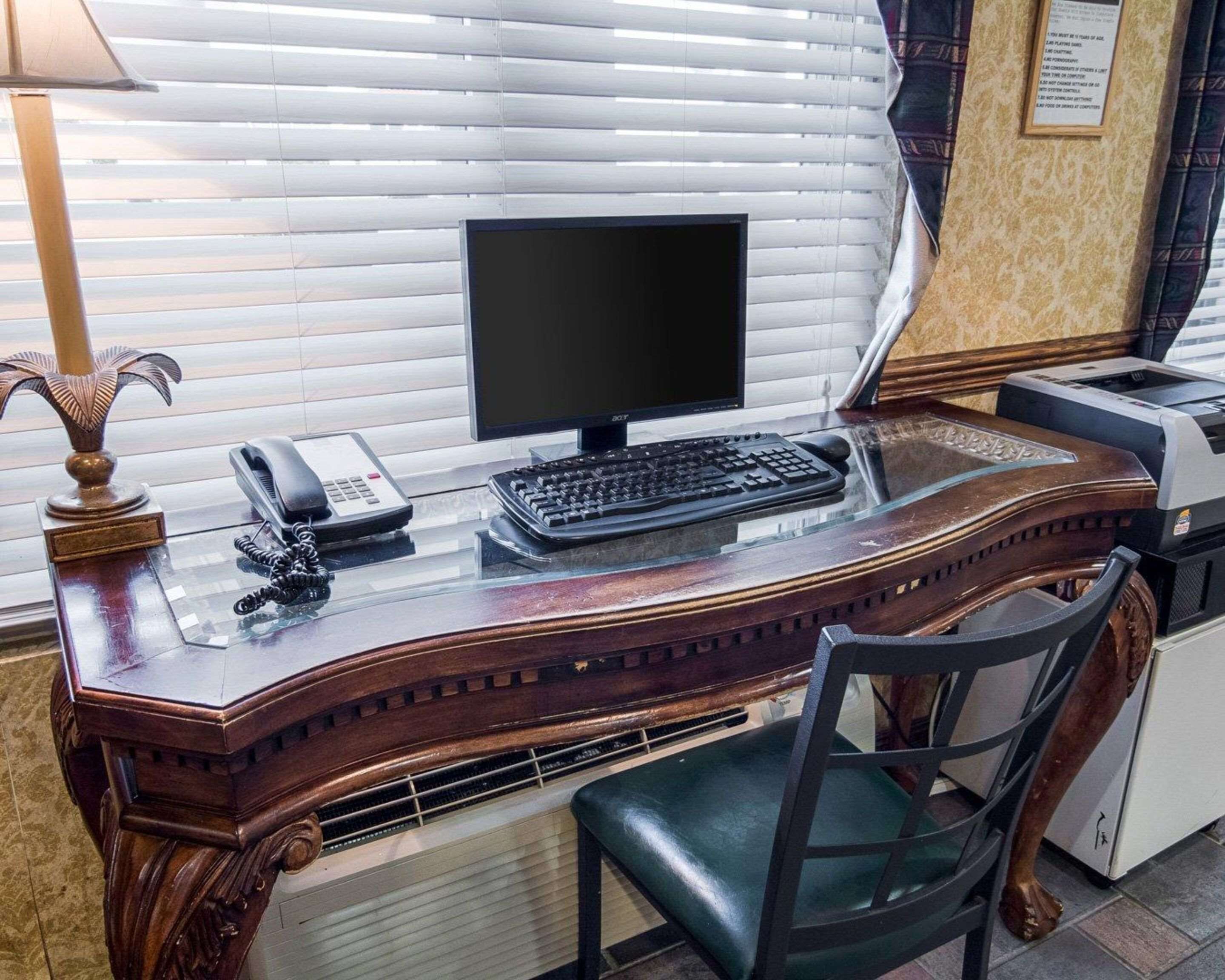 Un escritorio de madera con una computadora, un teléfono y una impresora.
