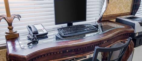 Un escritorio de madera con una computadora, un teléfono y una impresora.
