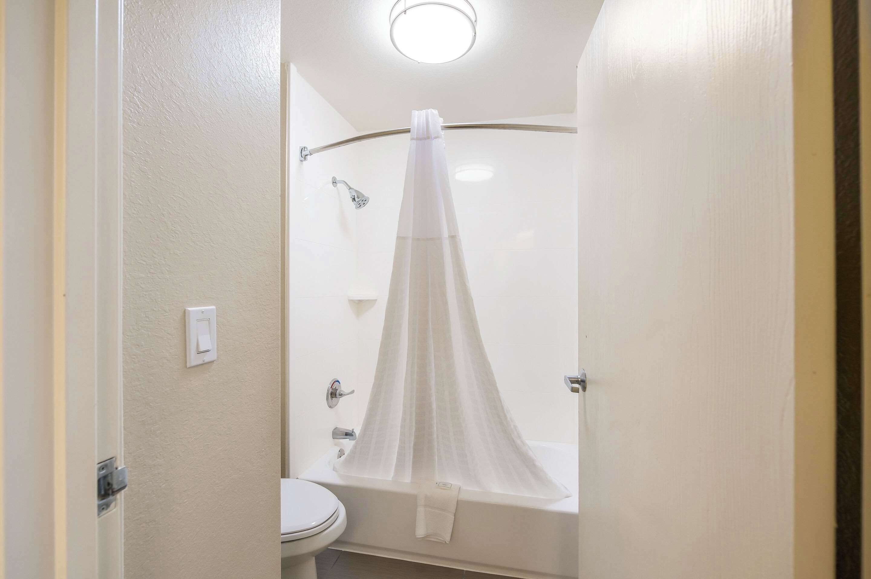 Un baño con ducha, inodoro y cortina.