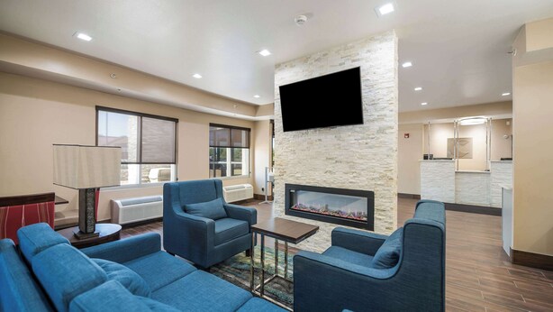 A modern living room with blue sofas, a flat-screen TV, a stone accent wall, and a fireplace. - Comfort Inn Bossier City Casino Area near Shreveport Downtown (Bossier City)