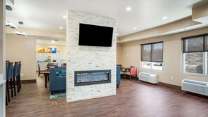 A spacious living area with a stone fireplace, a flat-screen TV mounted on the wall, and a dining area with chairs and a table. - Comfort Inn Bossier City Casino Area near Shreveport Downtown (Bossier City)