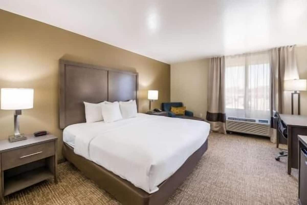 A hotel room with a large bed, bedside tables, a desk, and a chair.