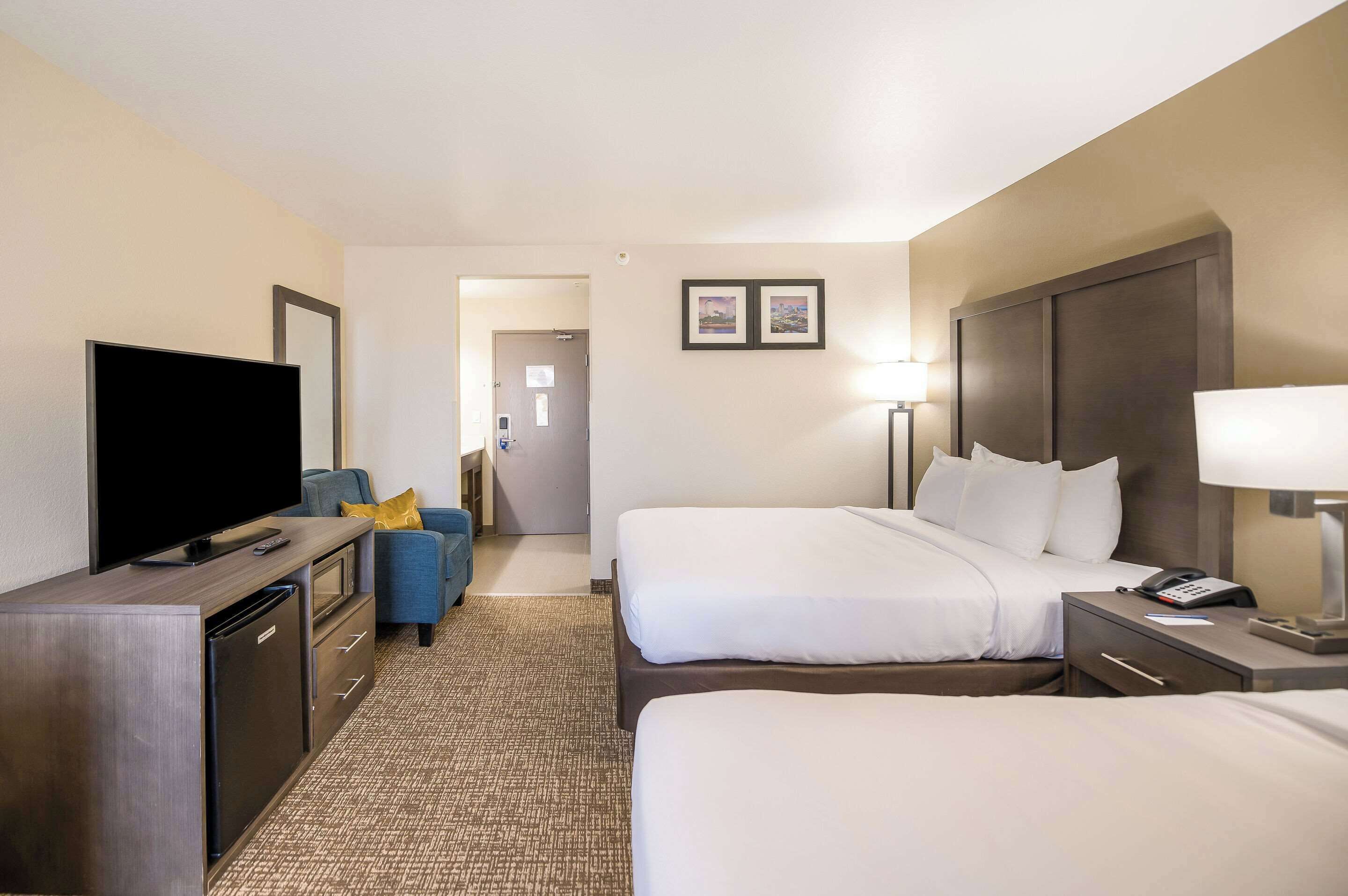 Une chambre d’hôtel avec deux lits, une télévision, un bureau et une chaise.