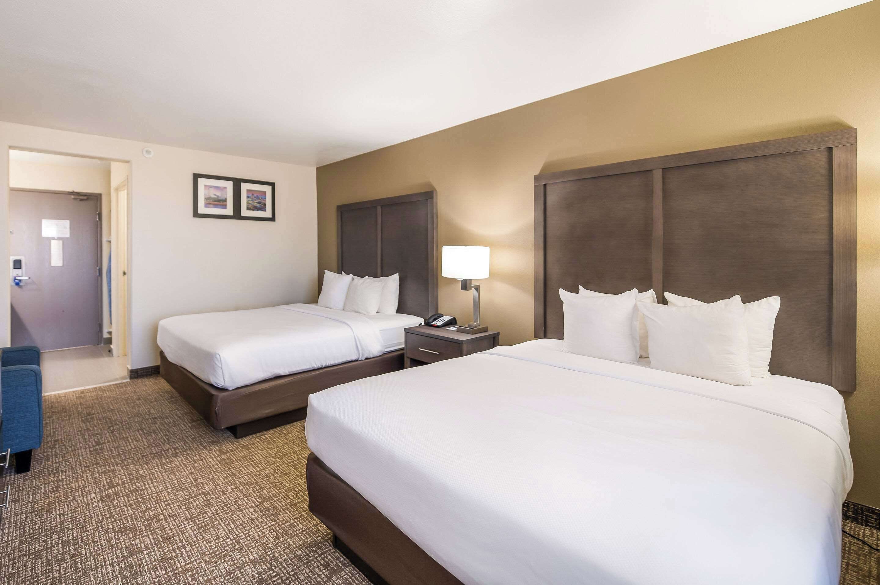Une chambre d’hôtel avec deux lits, un bureau et une chaise.
