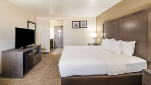A hotel room with a large bed, a flat-screen TV, a desk with a lamp, and a small refrigerator. - Comfort Inn Bossier City Casino Area near Shreveport Downtown (Bossier City)