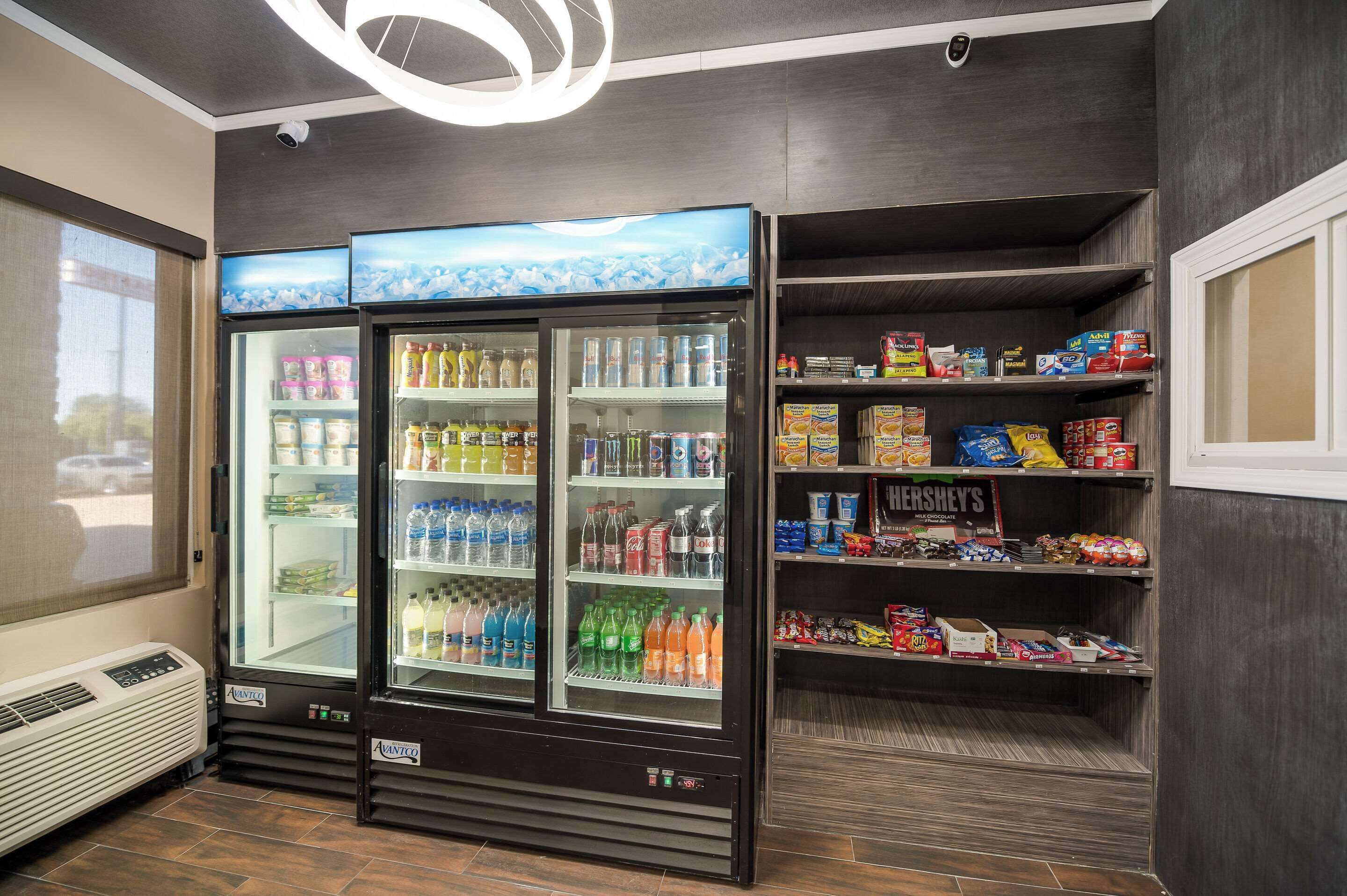 Un distributeur automatique proposant une variété de boissons et d’en-cas, une enseigne Hershey’s et une fenêtre avec des stores.