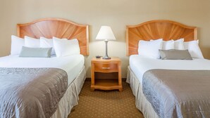 A hotel room with two beds, each with a wooden headboard, a nightstand with a lamp, and a small drawer. - Baymont by Wyndham Asheville/Biltmore Village (Asheville)
