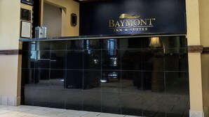 A Baymont Inn & Suites reception area with a dark reception desk, a sign above it, and a tiled floor. - Baymont by Wyndham Asheville/Biltmore Village (Asheville)