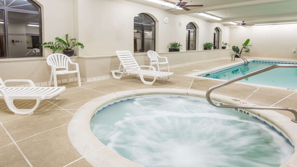 A hot tub with a metal railing, surrounded by white lounge chairs, and a tiled floor. - Baymont by Wyndham Asheville/Biltmore Village (Asheville)