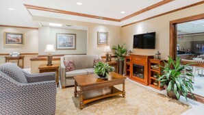 A living room with a sofa, armchairs, a coffee table, a fireplace, and a television. - Baymont by Wyndham Asheville/Biltmore Village (Asheville)