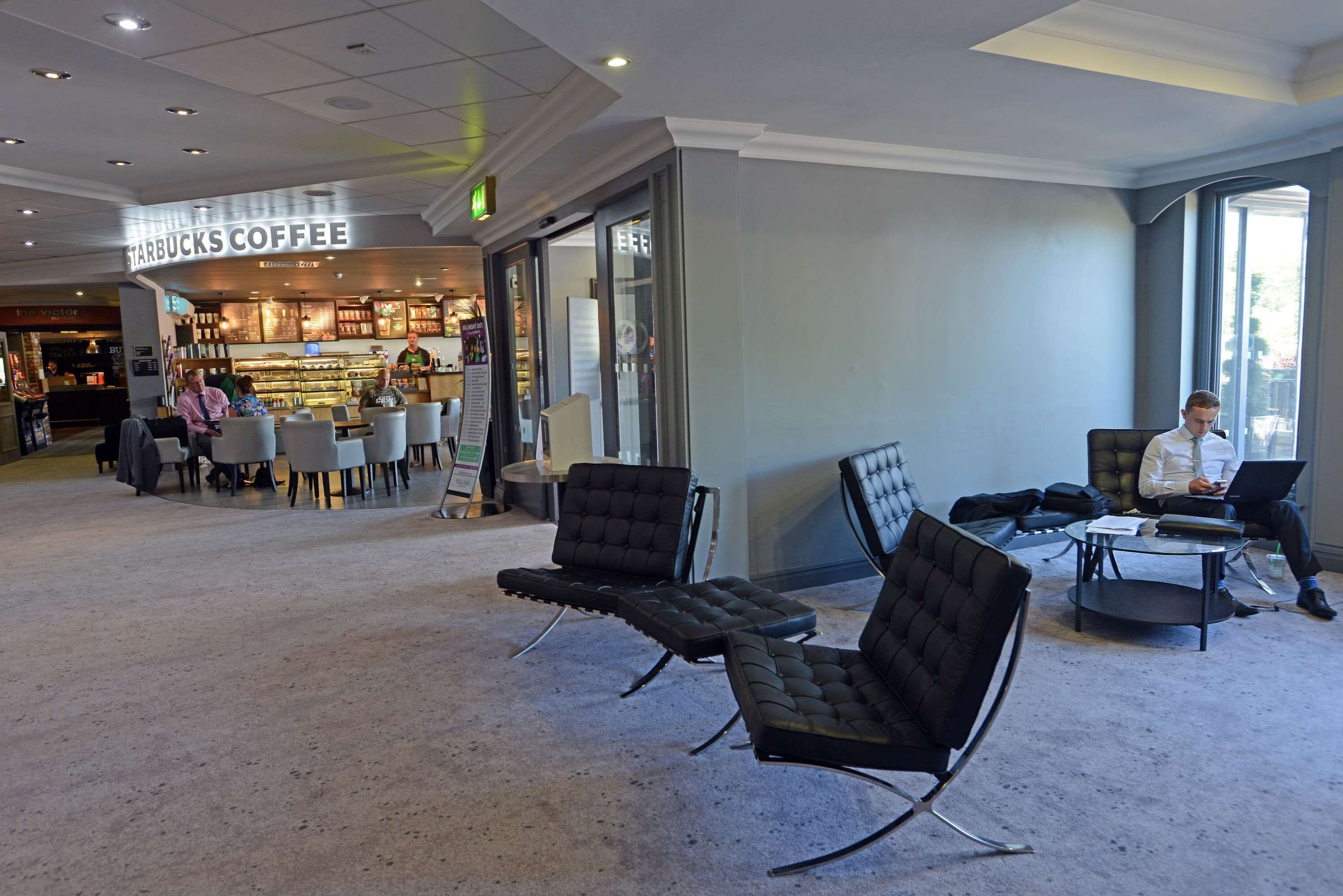 A Starbucks Coffee inside a building with seating areas and a large window.