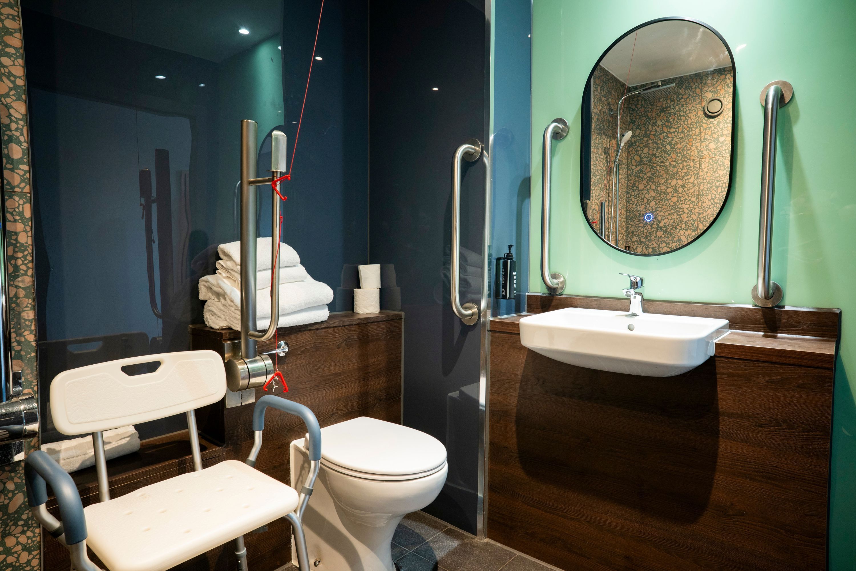 Un baño con inodoro accesible para sillas de ruedas, un lavamanos y un espejo.