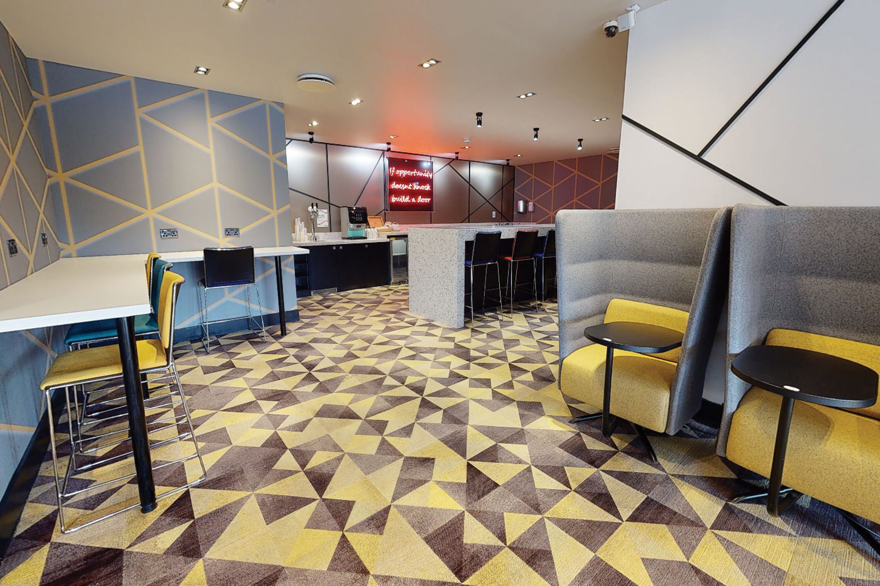 A modern hotel lobby with geometric patterned flooring, a reception desk, and seating areas.