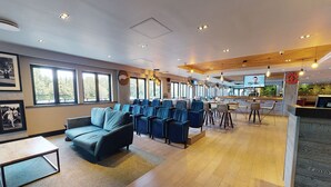 A modern hotel lobby with a seating area, a bar, and a television screen. - Village Hotel Coventry (Coventry)