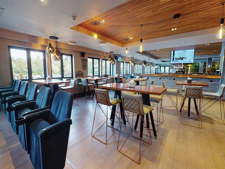 Un restaurante moderno con techo de madera, zona de bar y disposición de mesas.