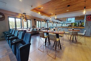 Restaurante moderno com teto de madeira, área de bar e disposição de mesas.