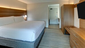 A hotel room with a large bed, wooden wardrobe, and a flat-screen TV.