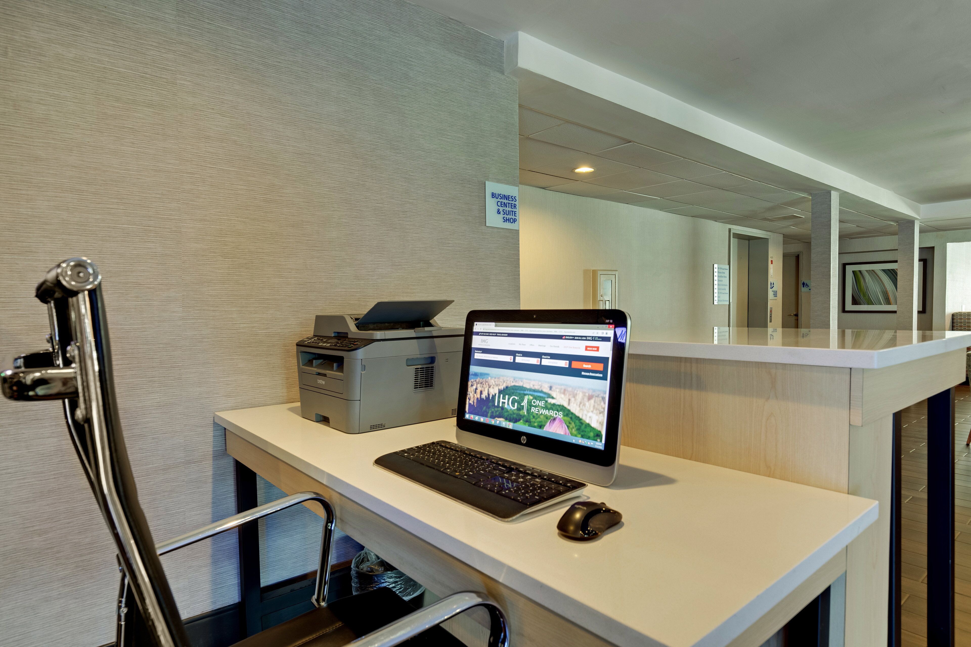 Un comptoir d’accueil d’hôtel équipé d’un ordinateur portable, d’un ordinateur de bureau et d’une imprimante.