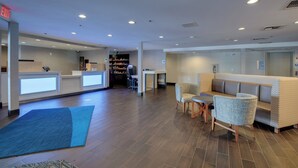 A hotel lobby with a reception desk, seating area, and a kitchenette in the background. - Holiday Inn Express W-I40/Whitebridge Road by IHG (Nashville)