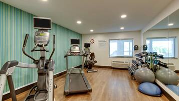 Un gimnasio con cintas de correr, elípticas y pelotas de ejercicio.