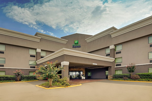 A Holiday Inn Express building with a modern design, large windows, and a landscaped entrance area.