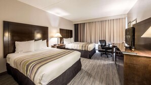 Een hotelkamer met twee bedden, een bureau, een stoel, een televisie en een lamp.