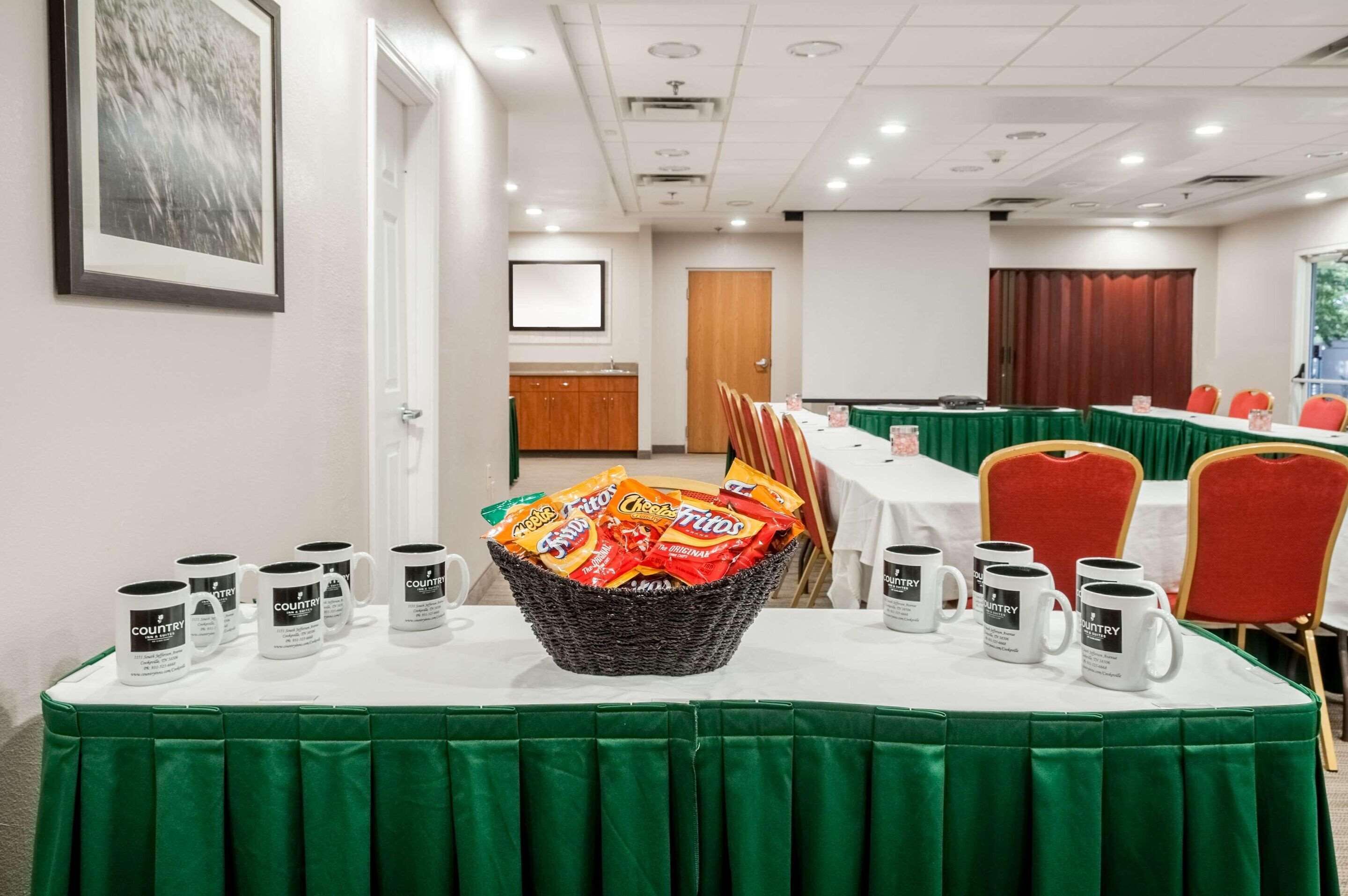 A conference room with a table set for a meeting, chairs, and a basket of snacks.