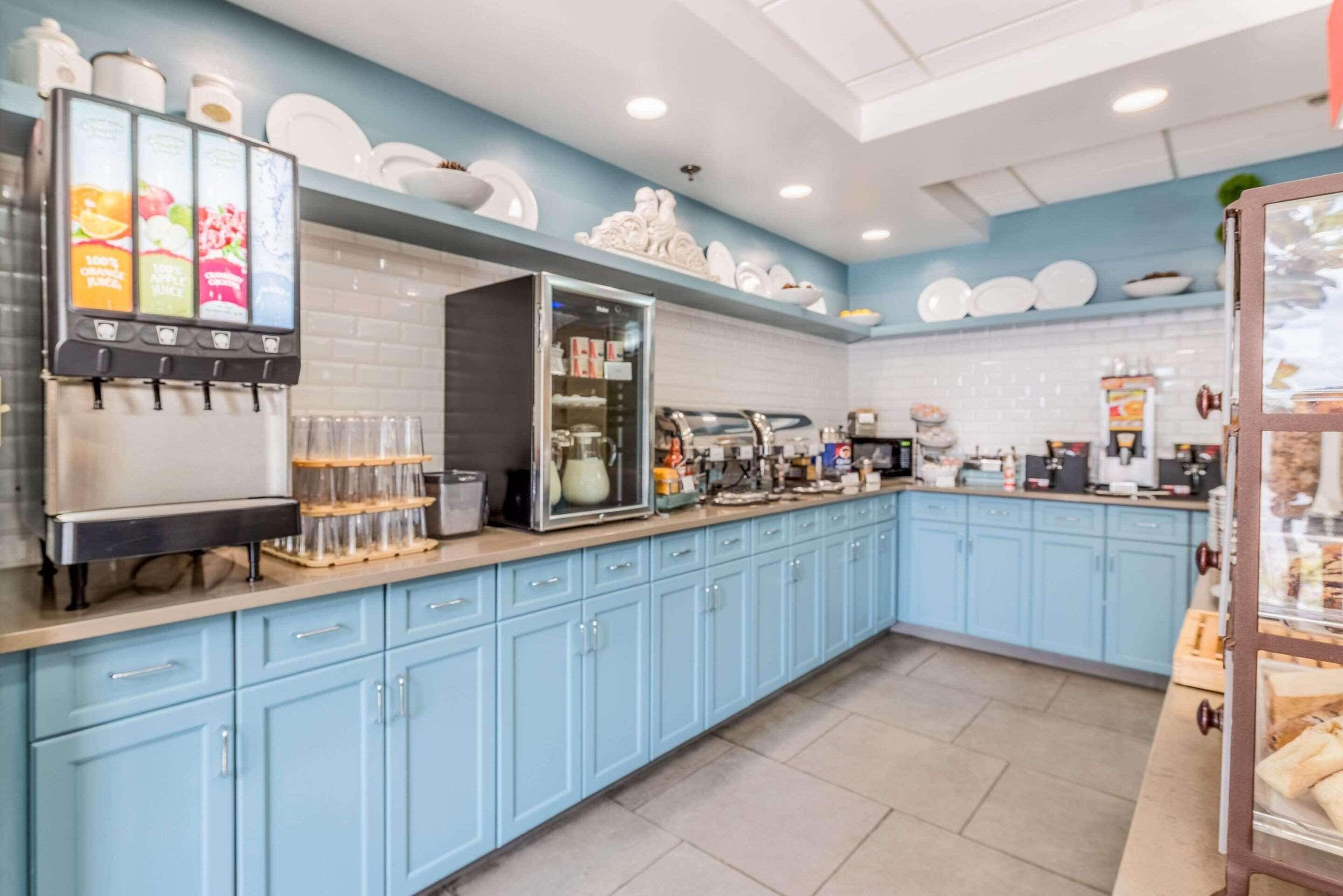 A commercial kitchen with light blue cabinets, a coffee machine, and a beverage dispenser.