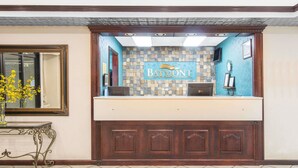 A reception desk with a Baymont sign, a mirror, and a vase with yellow flowers.