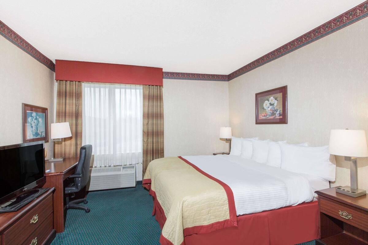 Een hotelkamer met een bed, bureau, televisie en twee lampen.