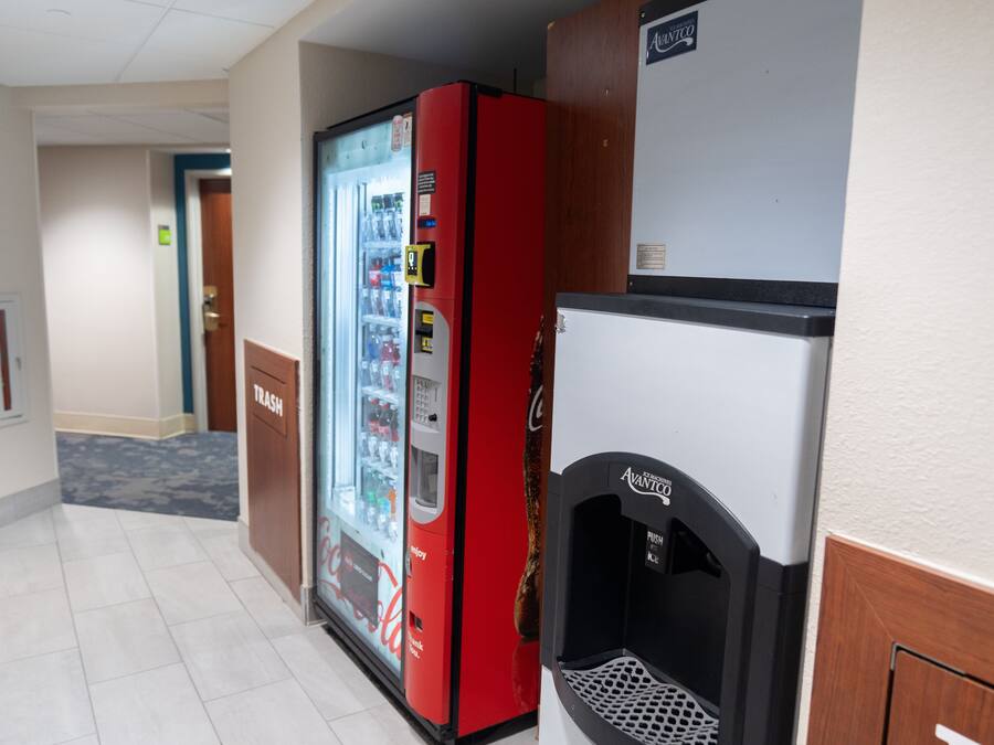 A hallway with a trash bin, a red vending machine, and a water dispenser.