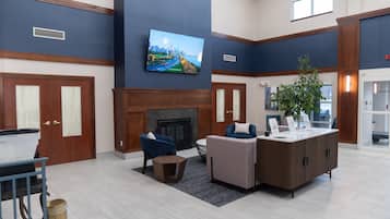 A lobby with a fireplace, seating area, and a television mounted on the wall.
