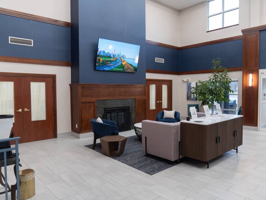 A lobby with a fireplace, seating area, and a television mounted on the wall.
