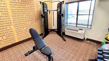 Un gimnasio con barra de dominadas, banco y alfombra estampada.