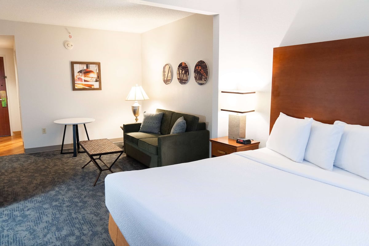 Een hotelkamer met een groot bed, een bank, een kleine tafel en een lamp.